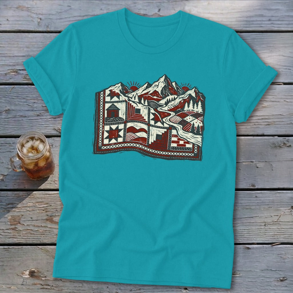 Teal t-shirt featuring a stylized graphic of a mountain landscape combined with quilt patterns.
