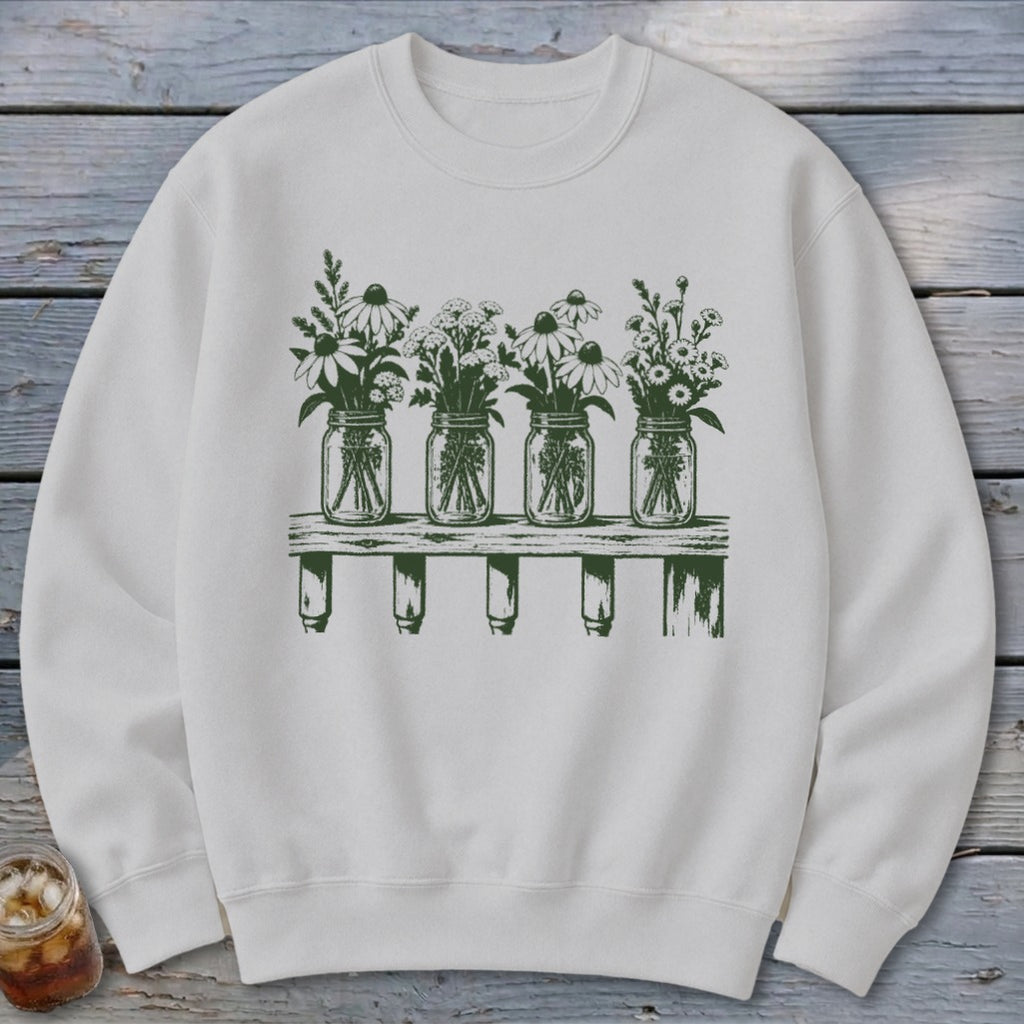 Light grey crewneck sweatshirt featuring a green botanical illustration of four mason jars with wildflowers on a shelf.