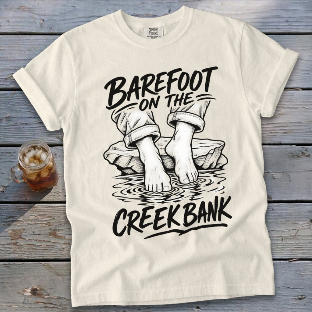 Cream t-shirt with "Barefoot on the Creek Bank" graphic featuring feet in water.