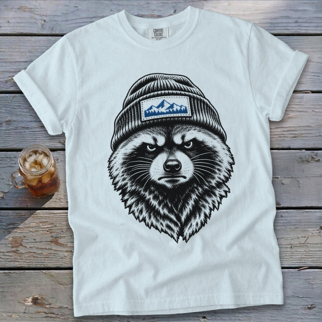 White t-shirt with a black and white illustration of a raccoon wearing a beanie with a mountain patch.