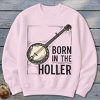 Pink crewneck sweatshirt with a banjo graphic and text "BORN IN THE HOLLER".