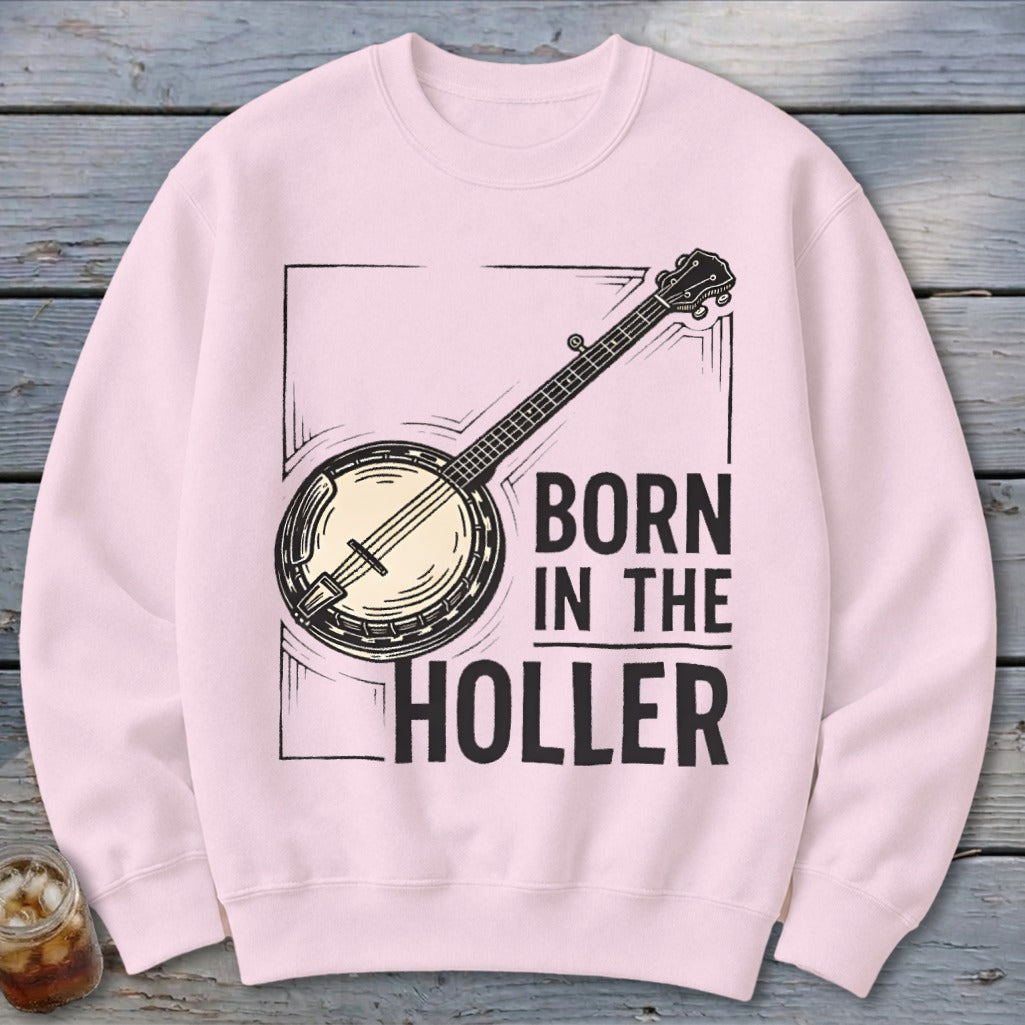 Pink crewneck sweatshirt with a banjo graphic and text "BORN IN THE HOLLER".