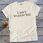 Cream t-shirt with black text reading "I AIN'T STUDYIN' YOU".
