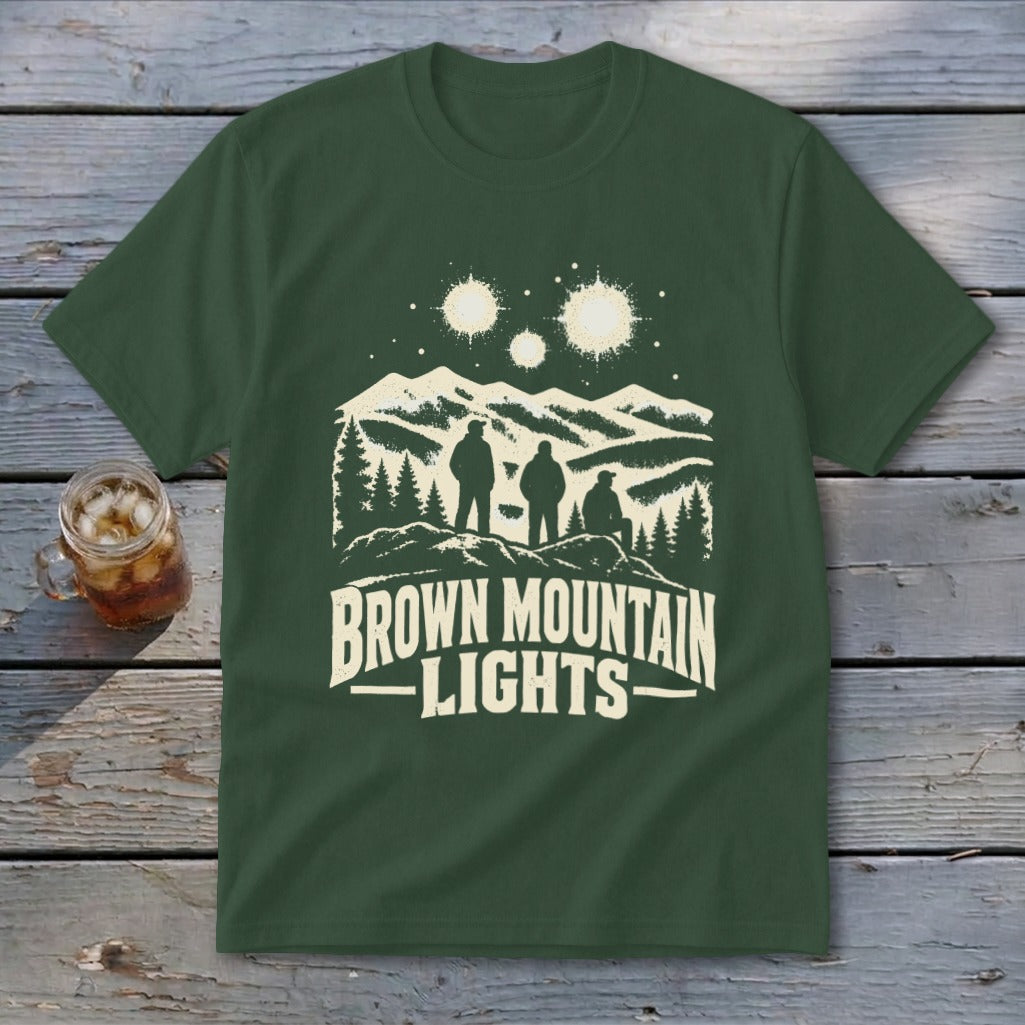 Dark green t-shirt featuring a graphic print of three people looking at glowing lights over mountains, with the text "BROWN MOUNTAIN LIGHTS".