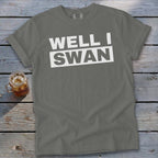 Grey t-shirt featuring the white text "WELL I SWAN" on a wooden background with a glass of iced tea.