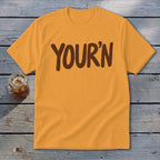 Orange t-shirt with brown "YOUR'N" text, beside a glass of iced beverage.