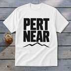 A white t-shirt featuring the text "PERT NEAR" in bold black font above a mountain silhouette.