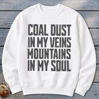 A white crewneck sweatshirt features bold black text reading Coal Dust in My Veins, Mountains in My Soul.