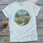 White t-shirt with circular graphic of North Carolina mountains, river, deer, and sun.