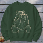 Bear sitting cross-legged, playing a harmonica, on a dark green sweatshirt.