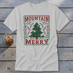 Light gray t-shirt featuring a vintage Christmas tree graphic with the text Mountain Merry on a rustic wooden background.