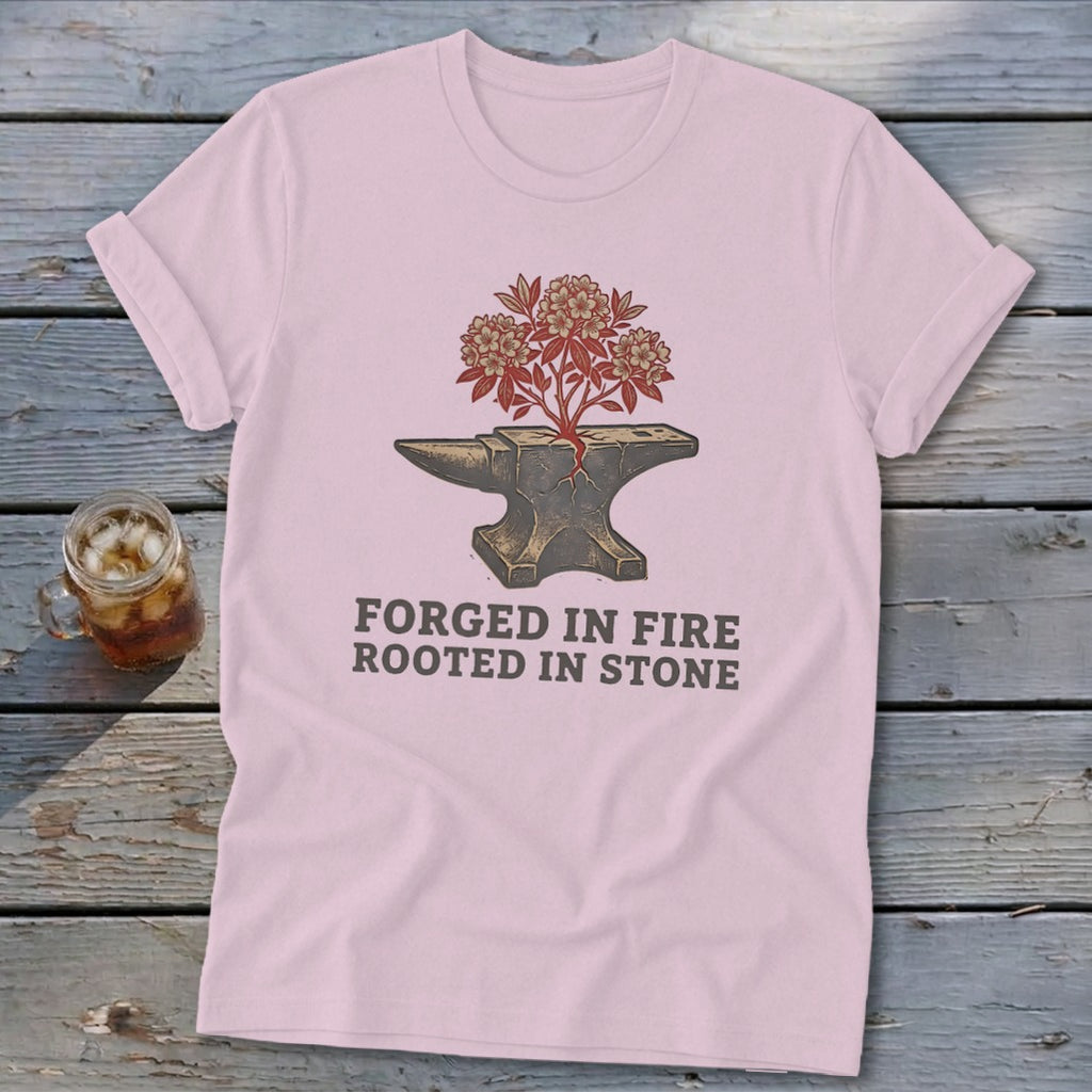 Pink t-shirt with anvil, blooming plant, and text "FORGED IN FIRE ROOTED IN STONE."