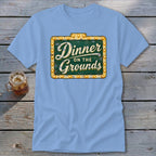 A light blue t-shirt featuring a green sign graphic that reads Dinner on the Grounds.