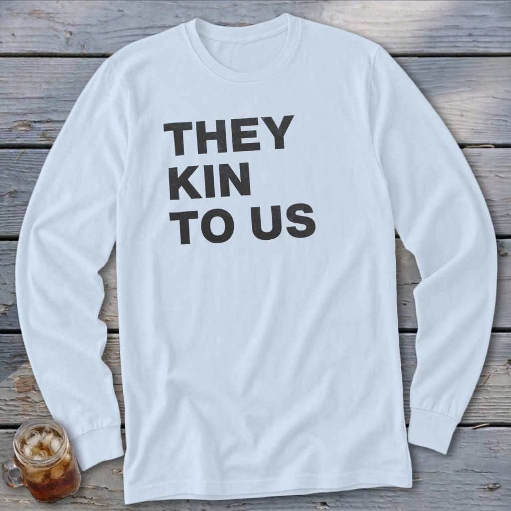 White long-sleeve shirt with black text "THEY KIN TO US"