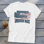 White t-shirt with a distressed graphic of an American flag and the text Mississippi Raised American Made.
