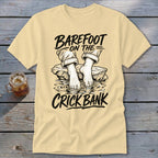 Cream t-shirt with graphic: "Barefoot on the Crick Bank" and feet in water.