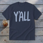 Navy t-shirt with light blue "Y'ALL" text, on a wooden background.