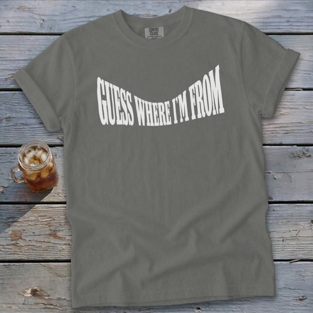 Grey t-shirt with white text "GUESS WHERE I'M FROM" in a curved font.