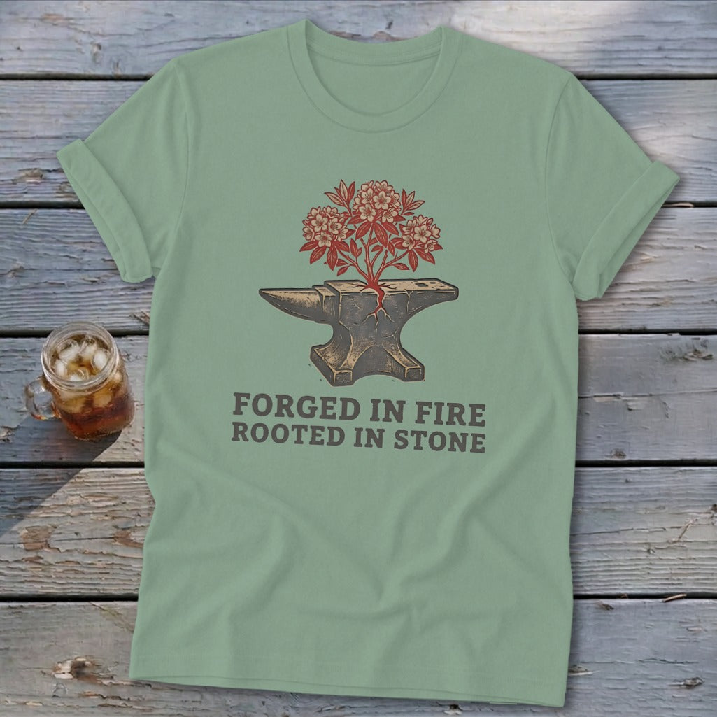 Green t-shirt with anvil, flowering plant, and text "FORGED IN FIRE ROOTED IN STONE".