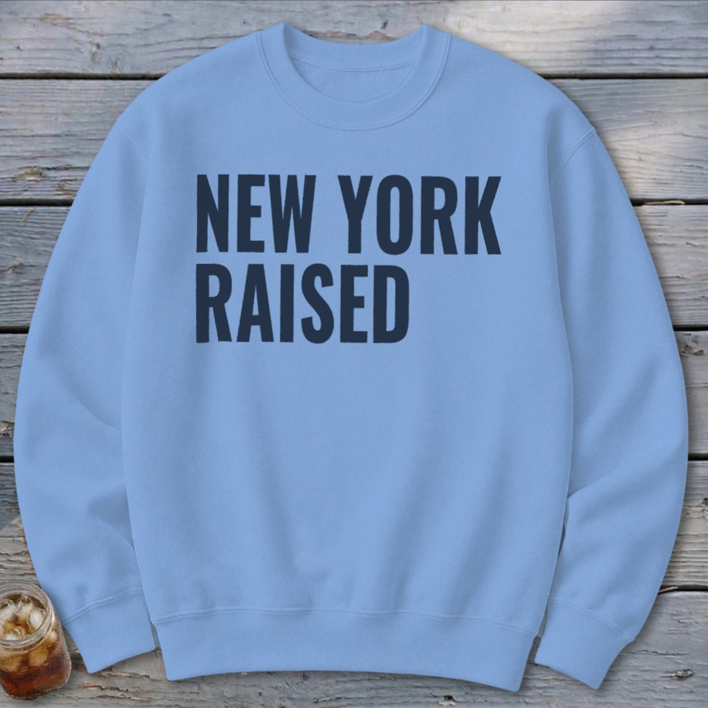 Light blue sweatshirt with "NEW YORK RAISED" printed in dark blue text.