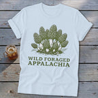 Light blue t-shirt with green illustration of morel mushrooms and text "WILD FORAGED APPALACHIA".