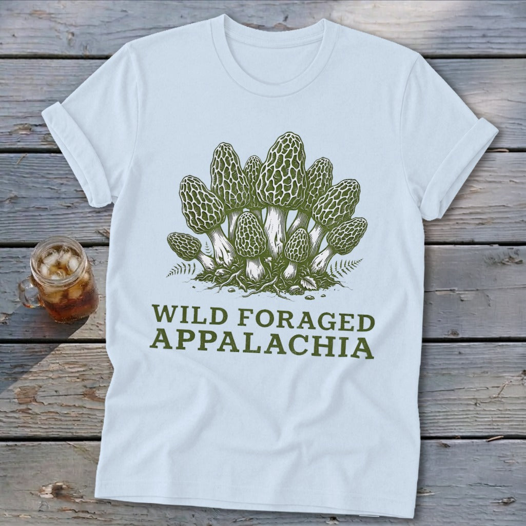 Light blue t-shirt with green illustration of morel mushrooms and text "WILD FORAGED APPALACHIA".