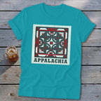 A bright teal short-sleeve t-shirt features a square red, white, and black geometric quilt block graphic with the text Appalachia underneath.