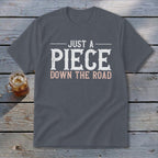 Gray t-shirt with text "JUST A PIECE DOWN THE ROAD".