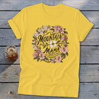 Yellow t-shirt with "Mountain Mama Raised Em Right" text and floral wreath design.