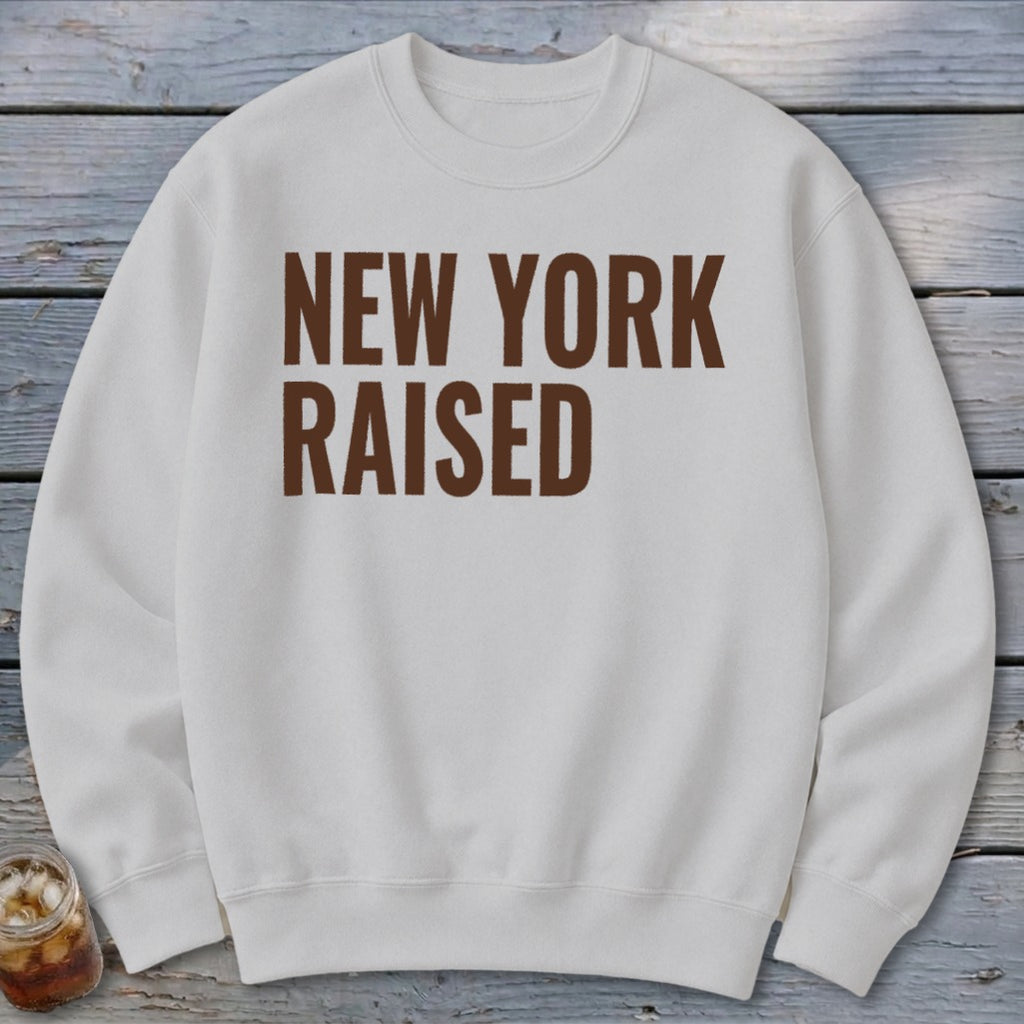 White sweatshirt with "NEW YORK RAISED" in brown block letters.