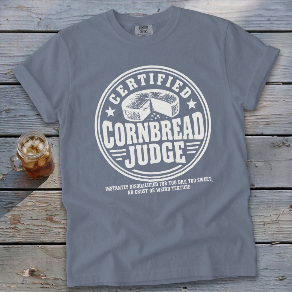 Blue t-shirt featuring a white graphic that reads "Certified Cornbread Judge" with a wheel of cornbread.