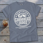 Blue t-shirt featuring a white graphic that reads "Certified Cornbread Judge" with a wheel of cornbread.