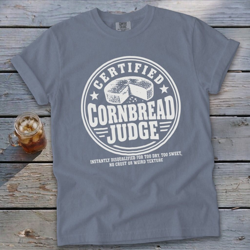Blue t-shirt featuring a white graphic that reads "Certified Cornbread Judge" with a wheel of cornbread.