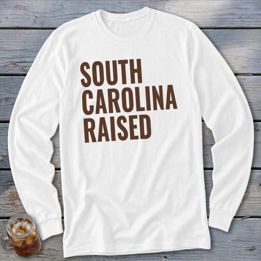 White long-sleeved shirt with brown text "SOUTH CAROLINA RAISED"