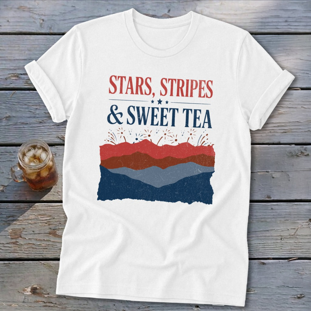A white t-shirt with rolled sleeves features red, white, and blue text reading "STARS, STRIPES & SWEET TEA" above a landscape design of layered hills and fireworks.