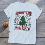 White short-sleeved t-shirt featuring a green and red Christmas tree design with the text Mountain Merry.
