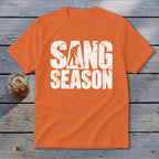 Orange short-sleeve t-shirt with white distressed text reading SANG SEASON and a digging silhouette.