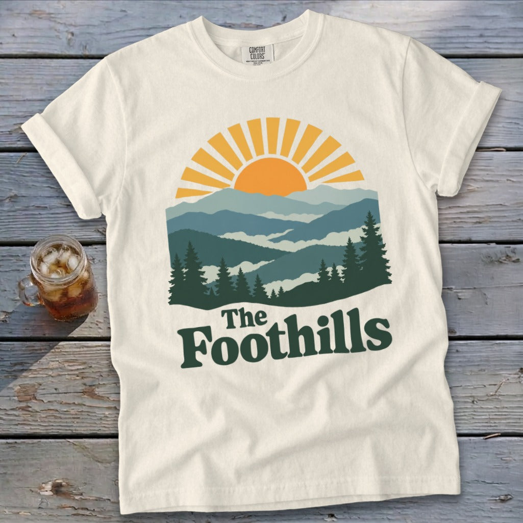Cream t-shirt with "The Foothills" text and a mountain landscape graphic.