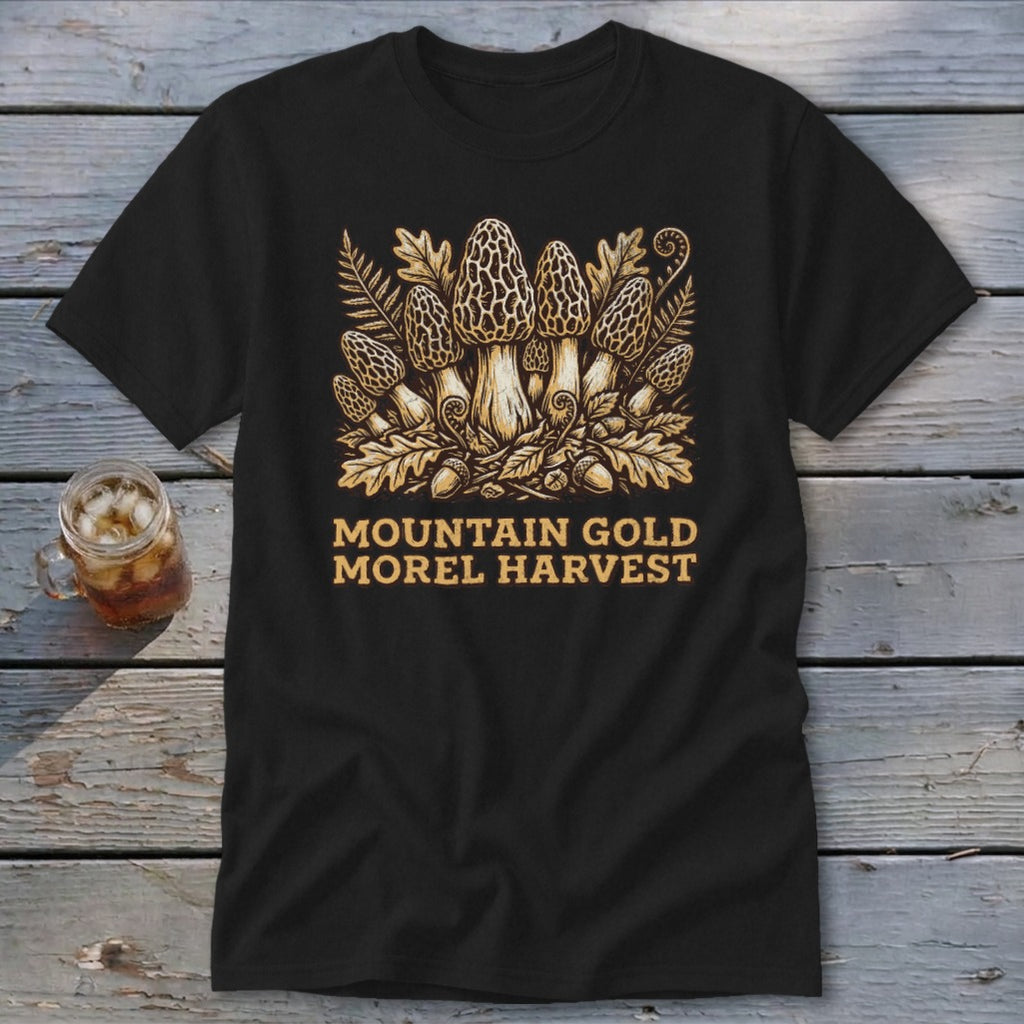 Black t-shirt with a golden illustration of morel mushrooms, ferns, and acorns. Text reads "Mountain Gold Morel Harvest".