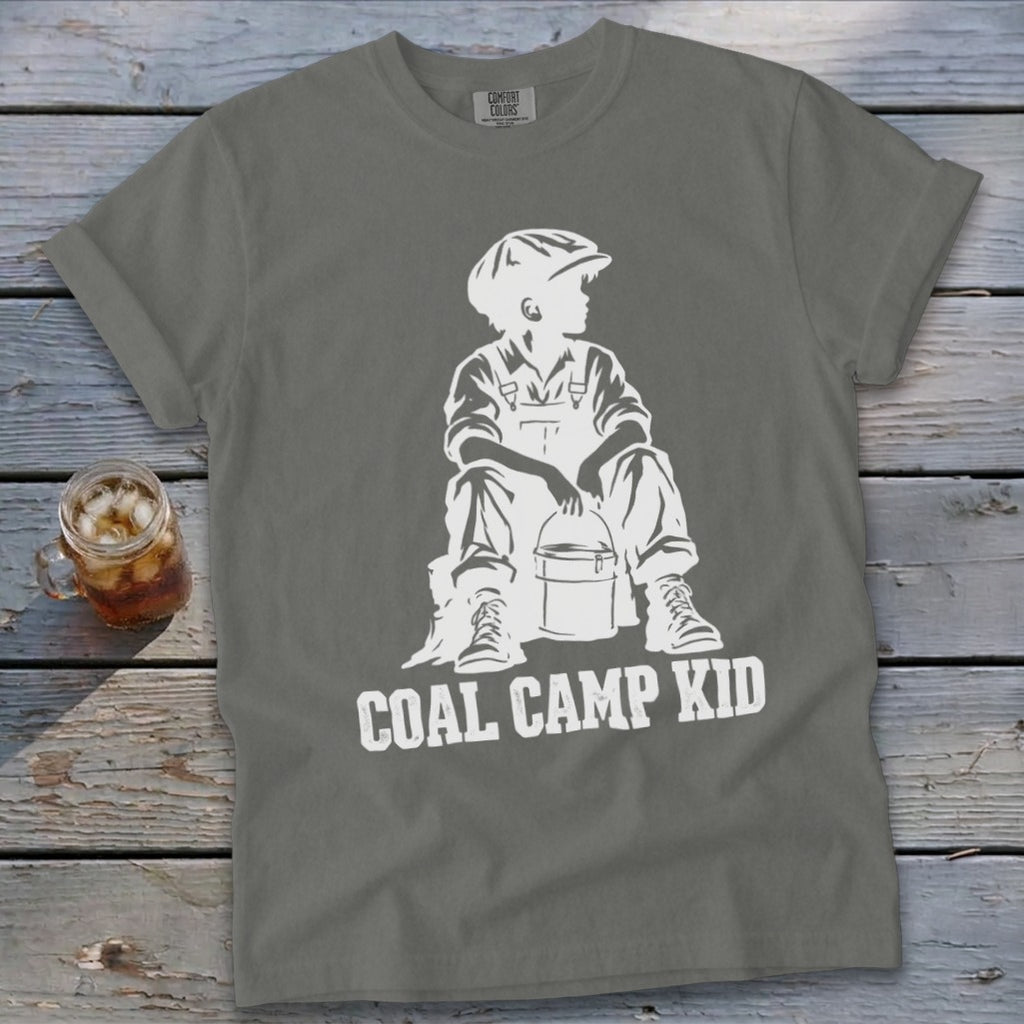 Grey t-shirt with white graphic of a seated boy in overalls and cap holding a bucket, text reads "Coal Camp Kid."