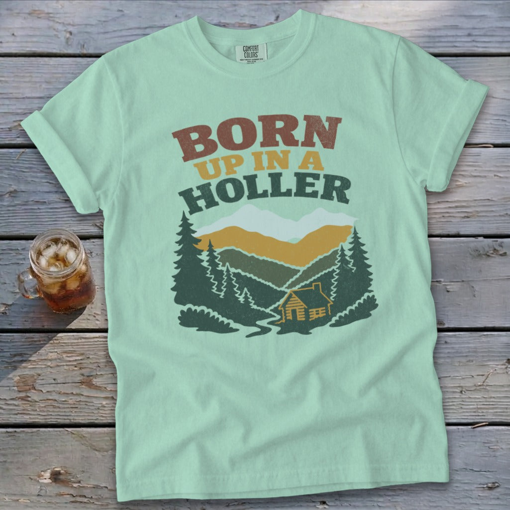 Mint green t-shirt with "BORN UP IN A HOLLER" and a cabin in the woods scene.