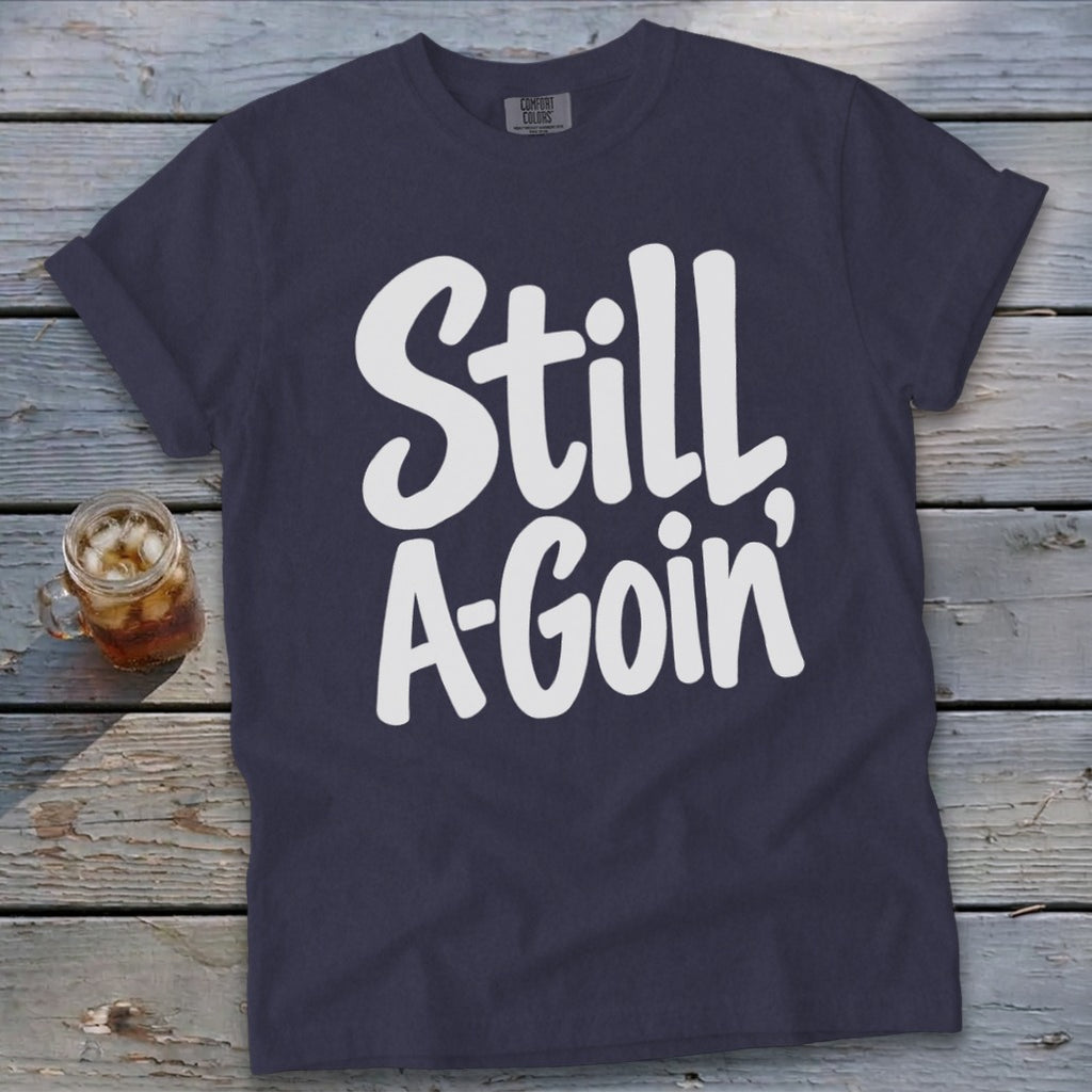 A navy blue crewneck t-shirt with white lettering that reads Still A-Goin'.