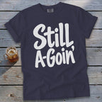 A navy blue crewneck t-shirt with white lettering that reads Still A-Goin'.
