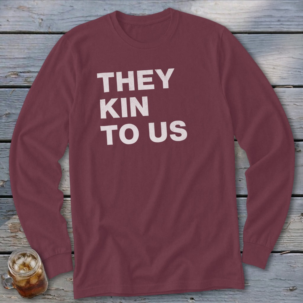 Maroon long sleeve shirt with white text "THEY KIN TO US".