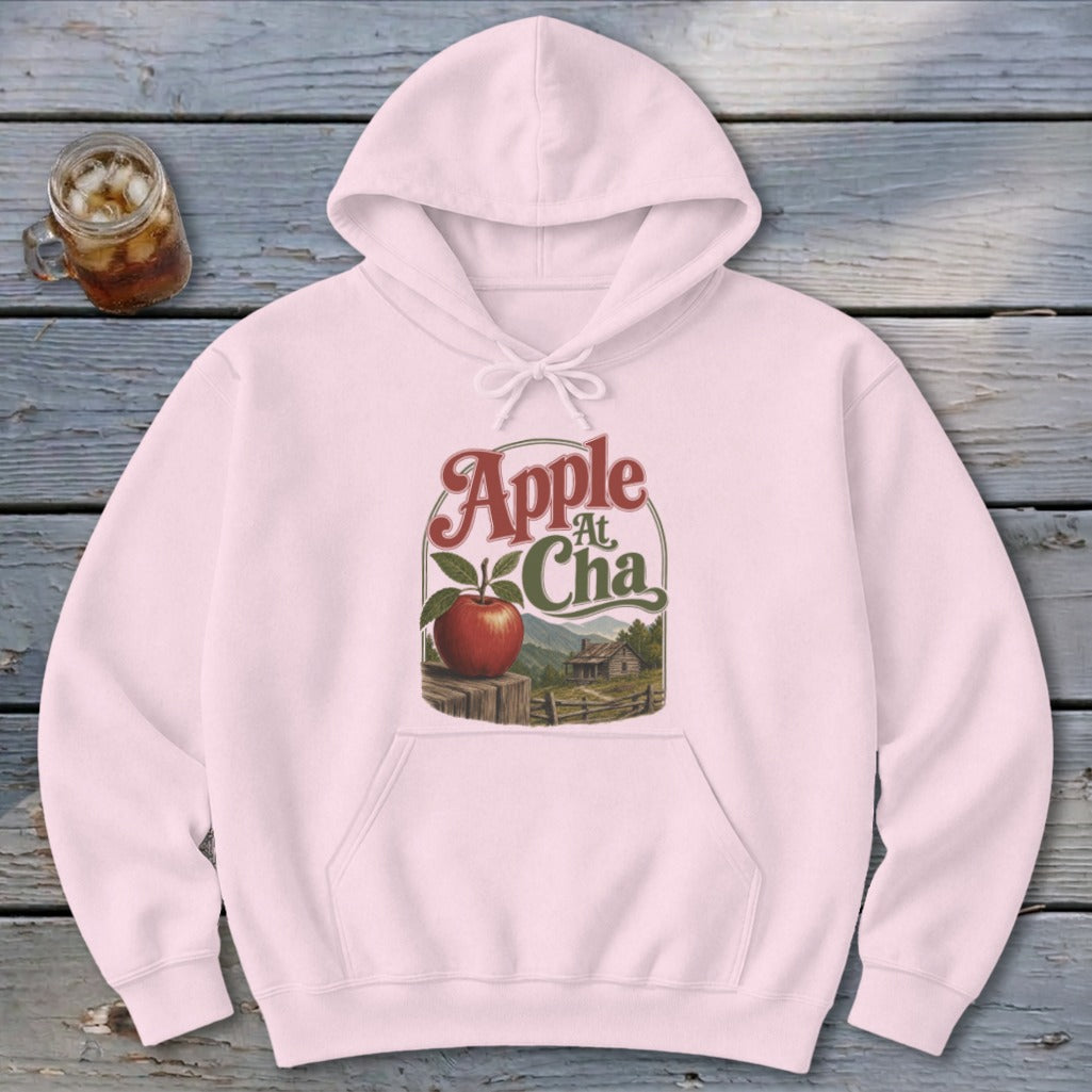 Light pink hoodie featuring a graphic of an apple and a cabin with text Apple at Cha.