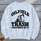 White sweatshirt with black text and oil pump graphic reading "Oilfield Trash and Proud of It".