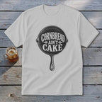 White t-shirt with "Cornbread Ain't Cake" graphic inside a cast iron skillet.