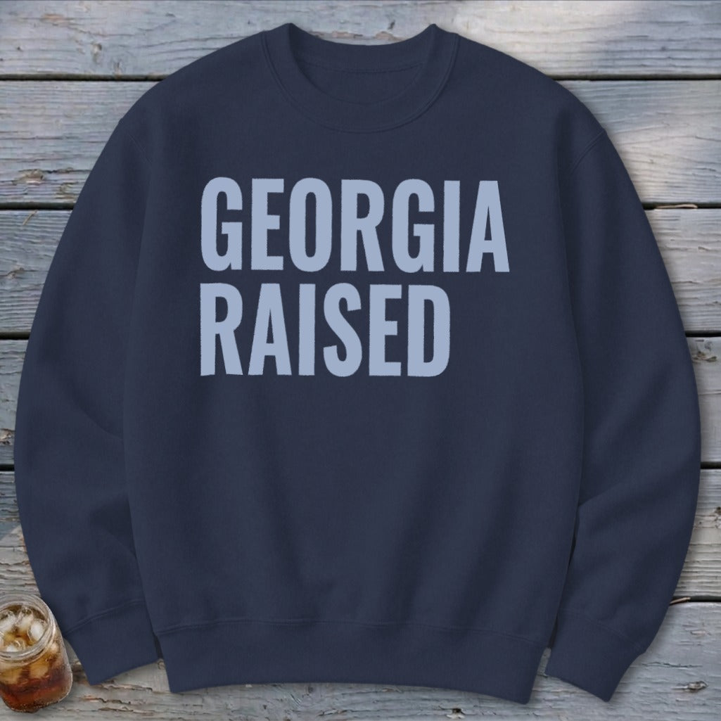 Navy sweatshirt with light blue text reading "GEORGIA RAISED".