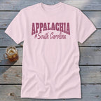 Pink t-shirt with "APPALACHIA #South Carolina" graphic, on a wooden surface.