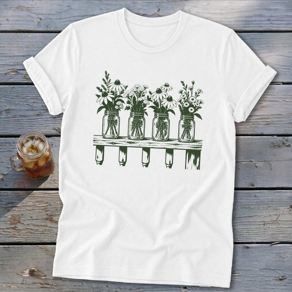 White t-shirt featuring a dark green graphic of four mason jar vases with flowers on a wooden shelf.